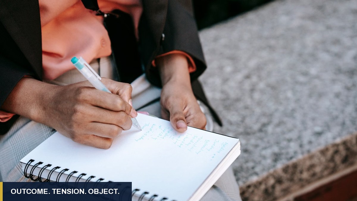 Hands writing a list in a spiral notebook